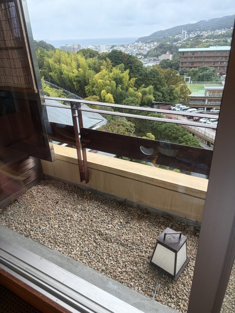 客室の窓から見た景色。手前に竹林、その先に伊東の街並みと海が見える