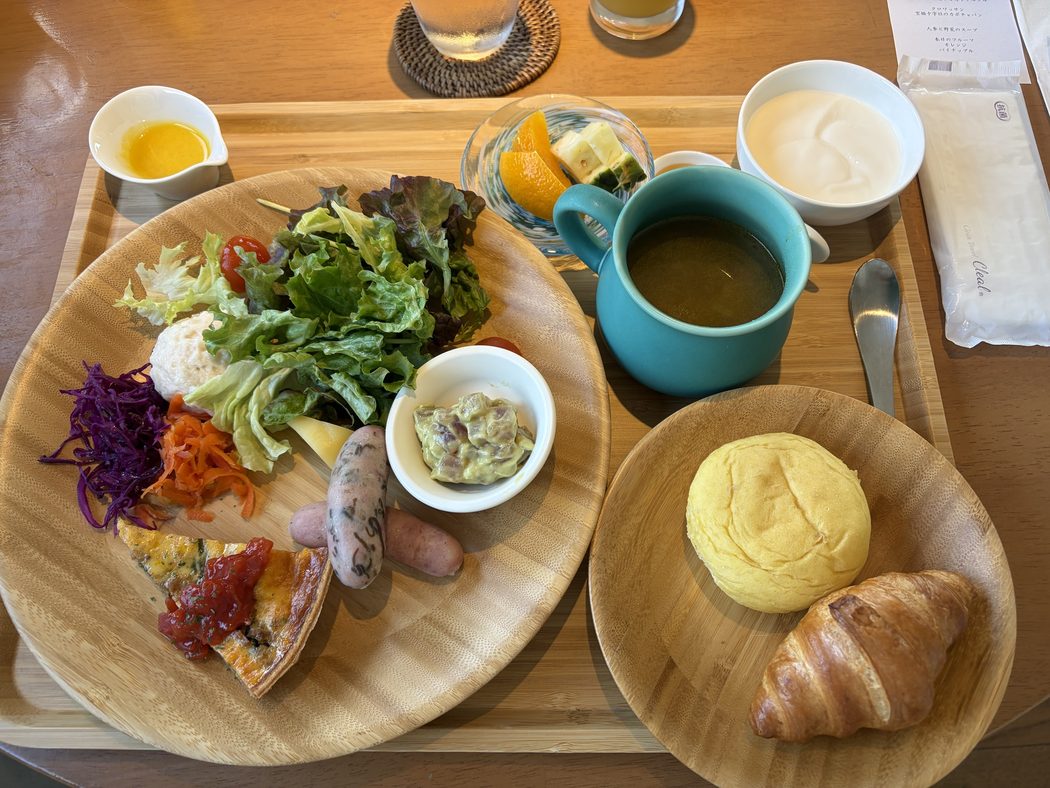 ザ・リスケープの朝食。キッシュとソーセージとサラダの皿、カボチャのパンとクロワッサン、人参と野菜のスープ、ヨーグルト、オレンジとパイナップル
